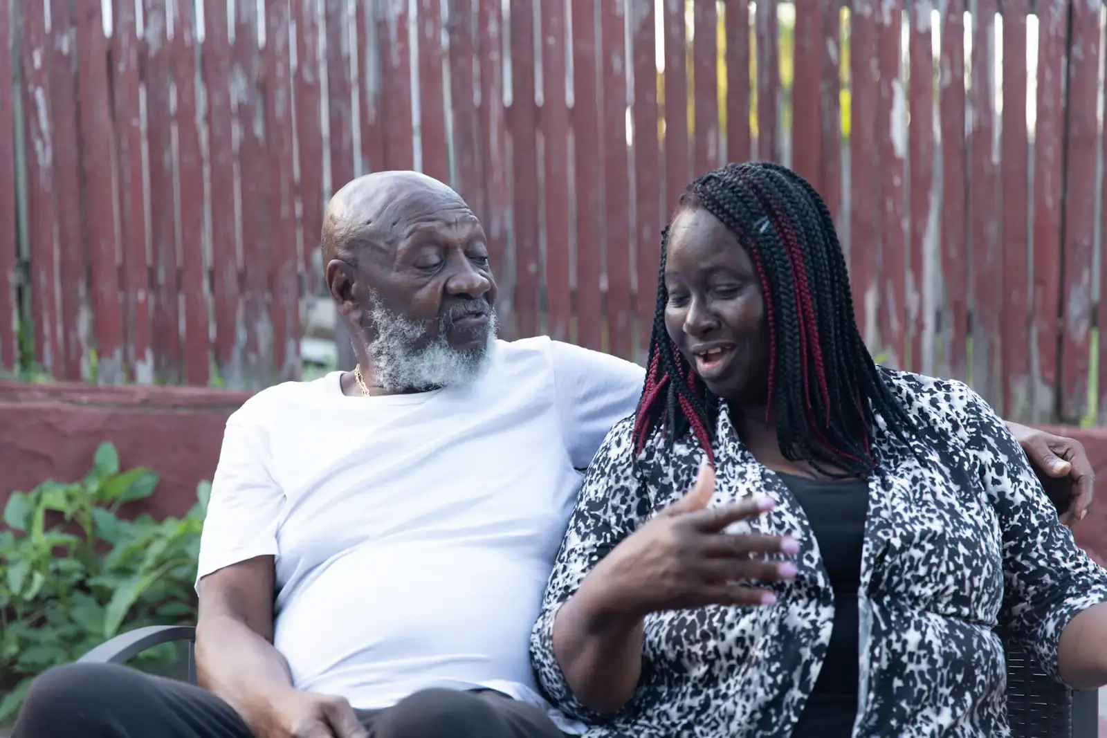 An older man in conversation with a caregiver outdoors