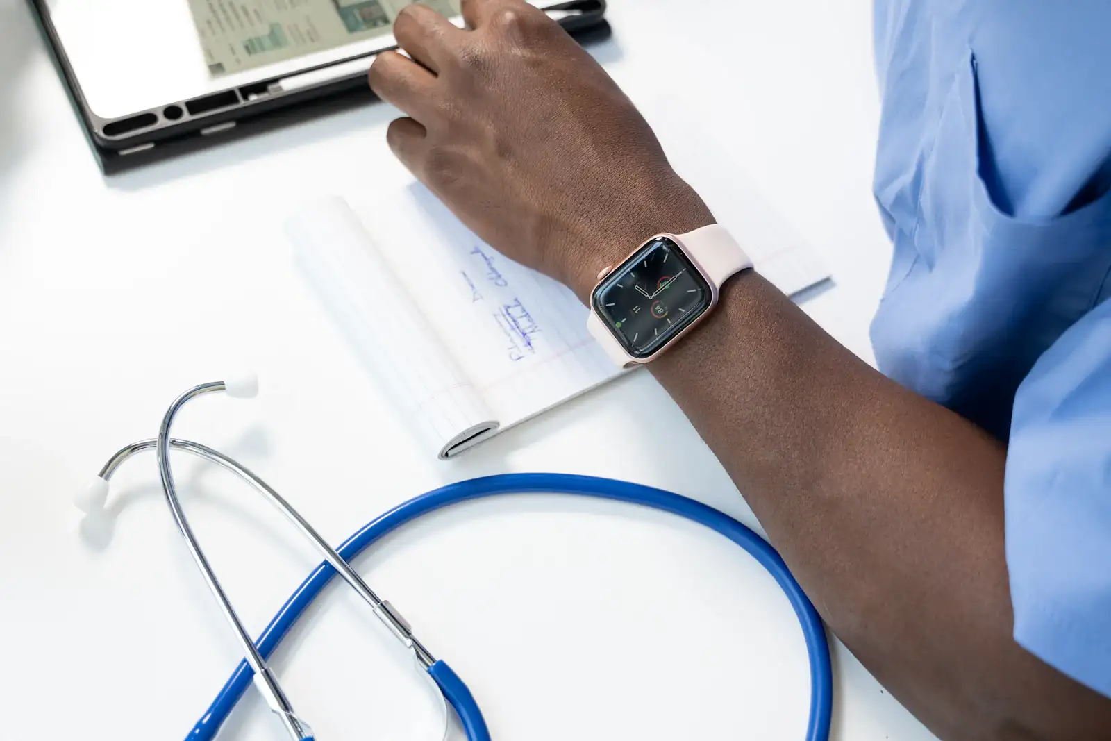 A clinician writing up medical notes beside a stethoscope