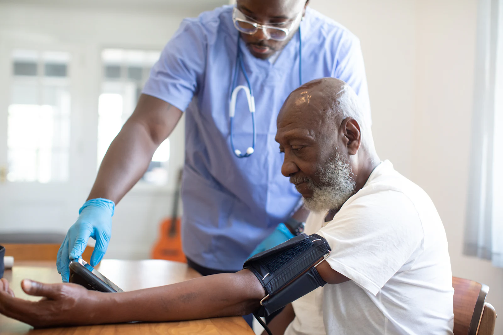 A nurse checking an older man's blood pressure during a medical assessment